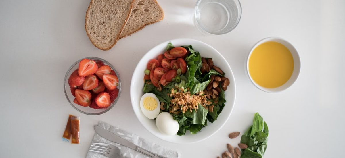 Top view of a nutritious breakfast with salad, eggs, bread, and juice, perfect for a healthy start.