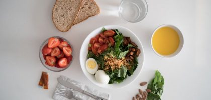 Top view of a nutritious breakfast with salad, eggs, bread, and juice, perfect for a healthy start.