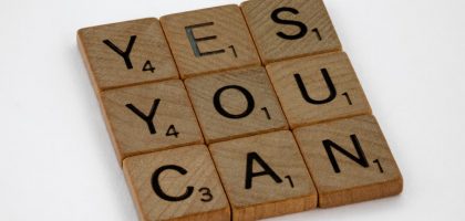 Wooden Scrabble tiles on white surface spelling 'Yes You Can,' promoting positivity and motivation.